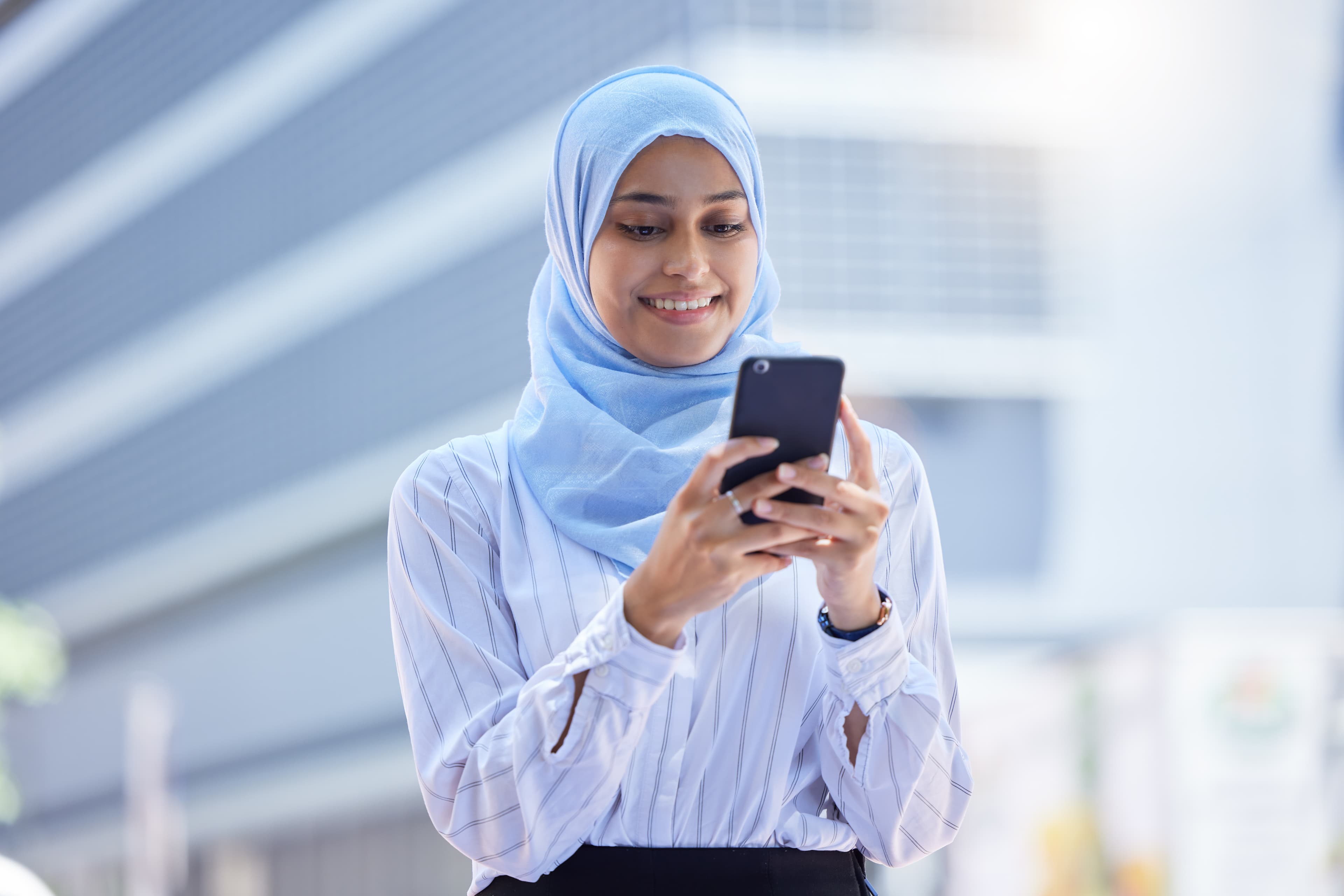 Islam, islamic or business woman on her phone in hijab texting in the city with mockup. Diversity, muslim and arabic international employee on mobile working in town or global corporate company